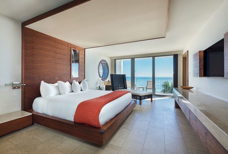 View of a king bed in a hotel guest room at Costa d'Este Beach Resort with a view of the ocean outside the window
