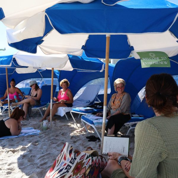 Group of women having conversation in blue and white cabanas on the beach