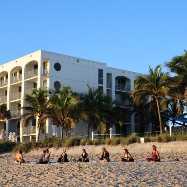 Group of women practice yoga on the sand at a beach resort